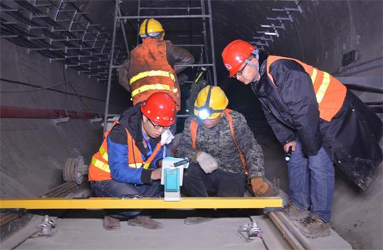 隨著我國(guó)公路建設(shè)規(guī)模的日益擴(kuò)大，公路隧道建設(shè)取得了很大的發(fā)展,公路隧道具有斷面大，地質(zhì)條件和施工技術(shù)復(fù)雜等特點(diǎn)，加之設(shè)計(jì)時(shí)對(duì)地質(zhì)條件的認(rèn)識(shí)不夠全面準(zhǔn)確，通車后存在的隧道老化、運(yùn)營(yíng)管理和維護(hù)等方面的原因，致使我國(guó)公路隧道的病害問(wèn)題十分嚴(yán)重，隧道襯砌背后的空洞問(wèn)題就是其一，由此引起的拱頂上鼓及襯砌內(nèi)緣壓裂、掉塊的現(xiàn)象嚴(yán)重影響到公路隧道的使用壽命。因此加強(qiáng)對(duì)隧道襯砌背后空洞的檢測(cè)判斷和處理，是隧道工程病害處理的重要一環(huán)。 一、檢查目的和必要性 目的：隧道拱部襯砌出現(xiàn)空洞剝落掉塊直接危及行車安全，但襯砌內(nèi)部病害隱蔽，無(wú)法通過(guò)肉眼發(fā)現(xiàn)，通過(guò)人工敲擊可有效發(fā)現(xiàn)襯砌內(nèi)部空洞等隱患，并對(duì)無(wú)損檢測(cè)資料有針對(duì)性的進(jìn)行驗(yàn)證。 必要性：通過(guò)隧道找部襯砌人工敲擊檢查?？蓪?duì)大部分拱部病害及早發(fā)現(xiàn)并進(jìn)行整治，從而降低運(yùn)營(yíng)期間拱部襯砌剝落掉塊的風(fēng)險(xiǎn)。 二、檢查時(shí)機(jī)和范圍 1、檢查時(shí)機(jī) 隧道二次襯砌貫通后，接觸網(wǎng)安裝前為最佳檢查時(shí)機(jī)，接觸網(wǎng)安裝后通電前次之，通電后則須停電 。 2、接觸網(wǎng)安裝前、后敲擊檢查的區(qū)別 接觸網(wǎng)安裝前后，敲擊方法、車輛、工具基本相同。主要區(qū)別： （1）接觸網(wǎng)作業(yè)車檢查平臺(tái)，升起高度或檢查架搭設(shè)高度不同，接觸網(wǎng)安裝前接觸網(wǎng)作業(yè)車檢查平臺(tái)升起高度或檢查架搭設(shè)高度距拱頂3米左右，拱頂至拱腰均易于敲擊，接觸網(wǎng)安裝后接觸網(wǎng)作業(yè)車檢查平臺(tái)升起高度，或檢查架搭設(shè)高度距離拱頂至少4米。 （2）檢查槌長(zhǎng)度不同。接觸網(wǎng)安裝前檢查槌長(zhǎng)度為2米左右，接觸網(wǎng)安裝后檢查槌長(zhǎng)度為2.5米至4.6米。 3、檢查范圍 當(dāng)使用供電檢查車或軌道車平板上搭檢查架檢查時(shí)，從拱頂中心線至起拱線半幅為一次敲擊檢查范圍，當(dāng)使用檢查架檢查時(shí)，從線路左側(cè)起拱線至線路右側(cè)起拱線全幅為一次敲擊檢查范圍。 圖片描述(最多50字) 三、檢查前準(zhǔn)備工作 1、車輛：接觸網(wǎng)檢查車，平板車搭檢查架，在鋼軌或側(cè)溝蓋板上推進(jìn)檢查架，以雙線隧道，軌頂至拱頂9米為例，且檢查平臺(tái)距接觸網(wǎng)立柱等侵限物體保持10至20厘米間距。 （1）采用接觸網(wǎng)檢查車檢查無(wú)接觸網(wǎng)時(shí)，檢查平臺(tái)高度以距拱頂3米為宜，檢查平臺(tái)橫向放置，有接觸網(wǎng)時(shí)，檢查平臺(tái)高度以距拱頂5米為宜，檢查平臺(tái)縱向放置，需要時(shí)再旋轉(zhuǎn)到橫向位置。 （2）平板車搭檢查架，鋼軌上安裝檢查架或側(cè)向水溝蓋板和兩線間底板頂搭設(shè)檢查架，無(wú)接觸網(wǎng)時(shí)，檢查平臺(tái)高度以距拱頂距離3米為宜，檢查平臺(tái)橫向?qū)挾瓤蛇_(dá)9米，有接觸網(wǎng)時(shí)，檢查平臺(tái)高度距離拱頂4米為宜，兩線間平臺(tái)需下凹0.5米，檢查平臺(tái)橫向?qū)挾瓤蛇_(dá)9.5米。 圖片描述(最多50字) 2、工具：大型工具有：接觸網(wǎng)檢查車、軌道車（含平板車）、檢查架（根據(jù)凈空定制）；小型工具有：手提式強(qiáng)光手電筒、頭部礦燈、檢查槌（空心鋼管直徑30mm，一端焊接一根尖頭鋼筋一端焊接一根平頭鋼筋，長(zhǎng)度2至4.6米不等），卷尺、塞尺、鋼直尺、噴漆、桶裝油漆、漆桿（4.5米長(zhǎng)竹竿一端綁扎油漆刷）、檢查梯、對(duì)講機(jī)、照相機(jī)、手套、安全帶、安全帽、防護(hù)衣、護(hù)目鏡、口罩、記錄本、黑水筆等。 3、人員：作業(yè)小組由8人組成（使用接觸網(wǎng)檢查車或軌道車時(shí)需1人持對(duì)講機(jī)指揮車輛），檢查車分工為：3人持檢查槌（敲擊半幅拱頂線路正上方拱腰，線路側(cè)方拱腰至起拱線），2人聽(tīng)敲擊音并標(biāo)記，1人記錄并拍照，1人指揮并負(fù)責(zé)安全檢查和提示，檢查架分工為：4人持檢查槌敲擊拱頂、拱腰，2人聽(tīng)敲擊音標(biāo)記并負(fù)責(zé)指揮及安全檢查提示，2人記錄并拍照。 四、敲擊檢查程序 1、開(kāi)窗安排：提前一天申請(qǐng)檢查天窗，天窗時(shí)間本線封鎖不少于8小時(shí)，鄰線限速每小時(shí)20公里，根據(jù)批準(zhǔn)的天窗計(jì)劃，駐站聯(lián)絡(luò)員在《行車設(shè)備登記簿》內(nèi)登記，列車高度員下達(dá)調(diào)度命令；施工負(fù)責(zé)人接到調(diào)度命令后按調(diào)度命令憑證發(fā)車；檢查車到指定地點(diǎn)后，立即設(shè)置防護(hù)體系。在距離檢查地點(diǎn)20米處現(xiàn)場(chǎng)防護(hù)員設(shè)置移動(dòng)停車信號(hào)彈（燈），在距離施工地點(diǎn)800米兩端防護(hù)員設(shè)置顯示停車手信號(hào)；鄰線防護(hù)需設(shè)置移動(dòng)減速信號(hào)牌和減速地點(diǎn)標(biāo)。天窗作業(yè)計(jì)劃結(jié)束前機(jī)車返回申請(qǐng)?？奎c(diǎn)。駐站聯(lián)絡(luò)員與現(xiàn)場(chǎng)防護(hù)員在執(zhí)行防護(hù)任務(wù)時(shí)，應(yīng)佩戴標(biāo)志攜帶通信設(shè)備，現(xiàn)場(chǎng)防護(hù)員還應(yīng)攜帶必要的防護(hù)用品；隨時(shí)掌握現(xiàn)場(chǎng)和列車運(yùn)行情況。發(fā)現(xiàn)異常情況及時(shí)通知車站值班員和施工負(fù)責(zé)人。駐站聯(lián)絡(luò)員應(yīng)與現(xiàn)場(chǎng)防護(hù)員時(shí)刻保持聯(lián)系。 圖片描述(最多50字) 2、敲擊作業(yè)：車輛行駛速度控制在每小時(shí)5公里以內(nèi)，檢查架推進(jìn)速度控制在每小時(shí)1公里以內(nèi)，行進(jìn)過(guò)程中進(jìn)行敲擊，憑敲擊聲音辨別是否存在空洞，聲音異常時(shí)停車仔細(xì)敲擊確認(rèn)空洞范圍，施工縫、混凝土修補(bǔ)、蜂窩、混凝土表面有雜物（如鋼筋頭、注漿管等）、施工冷縫、止水帶外露、防水板外露、閉環(huán)裂紋、變形外鼓等重點(diǎn)處所均停車進(jìn)行仔細(xì)敲擊檢查。 3、照明配置、照度、范圍：BAD305手提式防爆探照燈2臺(tái)，BAD212微型手持防爆調(diào)光工作燈2臺(tái)，LED722B充電頭燈2臺(tái)，照度不低于250勒克斯，照明可視距度10m。 4、敲擊人員自我防護(hù)注意事項(xiàng)：（1）作業(yè)前將勞動(dòng)防護(hù)用品穿戴整齊‘（2）攀爬腳手架時(shí)，要站穩(wěn)扶牢。登上檢查平臺(tái)后，須首先掛好安全帶和安裝欄桿扶手，工具應(yīng)放置穩(wěn)固。（3）接觸網(wǎng)檢查車檢查平臺(tái)、檢查架移動(dòng)前應(yīng)通知作業(yè)人員停止作業(yè)，將工具擺放穩(wěn)固，人員蹲下扶牢，目視前進(jìn)方向，機(jī)車指揮人員發(fā)現(xiàn)侵限物體要及時(shí)停車，拆除侵限物體。檢查架移動(dòng)就位后，必須設(shè)好滾輪制動(dòng)和斜撐后，方可作業(yè)。（4）檢查小組人員必須團(tuán)結(jié)協(xié)作、聽(tīng)從指揮，相互提醒安全注意事項(xiàng)，做到自控、互控。（5）人員站位要相對(duì)固定，避免檢查槌等工具碰傷人員。（6）清除襯砌掉塊時(shí)，應(yīng)高聲提醒所有人員注意安全，下方無(wú)人時(shí)，方可進(jìn)行作業(yè)。（7）鄰線來(lái)車時(shí)，須停止作業(yè)，小穩(wěn)扶牢，檢查工具不得侵限。 5、檢查架的組成：同槽鋼跑道、腳手架滾輪及抽動(dòng)裝置、 鋼管立柱、鋼管橫撐、鋼管斜撐、十字卡、萬(wàn)向卡、腳手板及鐵絲、欄桿及鎖口鋼筋、反光標(biāo)等組成。 6、缺陷確認(rèn)：敲擊聲音清脆，發(fā)出“鐺、鐺、鐺”的聲音說(shuō)明襯砌混凝土比較密實(shí)，如果敲擊聲音沉悶出現(xiàn)“咚、咚、咚”的聲音，說(shuō)明襯砌混凝土存在空洞，附帶檢查內(nèi)容包括襯砌掉塊、裂紋、滲漏水、露筋、鋼筋保護(hù)層厚度不足、蜂窩麻面、混凝土夾帶雜物等。 7、問(wèn)題標(biāo)記：發(fā)現(xiàn)問(wèn)題停車采用紅油漆標(biāo)記問(wèn)題范圍，測(cè)量（估算）相關(guān)尺寸，將病害類型、尺寸等數(shù)據(jù)詳細(xì)記錄、拍照存檔，如在空洞外邊界標(biāo)記面積范圍，在裂縫起終點(diǎn)位置用箭頭（箭頭朝向裂紋處）標(biāo)記長(zhǎng)度，箭頭旁標(biāo)出裂紋寬度值，同時(shí)將問(wèn)題類型、編號(hào)、里程用紅油漆在問(wèn)題位置邊墻上進(jìn)行標(biāo)記，以便日后整改。標(biāo)記形式“BLWKD-1-K493+179”，BLW指白力塢隧道，KD指拱部空洞，1指編號(hào)為1號(hào)，K493+179指空洞里程，若一個(gè)隧道有多處空洞，序號(hào)按里程從小到大排序，依次為1、2、3、4.......。 8、資料整理：為避免出現(xiàn)場(chǎng)檢查發(fā)現(xiàn)問(wèn)題記憶模糊、相似問(wèn)題相互混淆的情況，檢查小組每天須將當(dāng)天檢查發(fā)現(xiàn)的問(wèn)題，根據(jù)病害類型、部位、按靜態(tài)驗(yàn)收?qǐng)?bào)告格式進(jìn)行梳理、統(tǒng)計(jì)，將照片編輯相應(yīng)文字說(shuō)明。